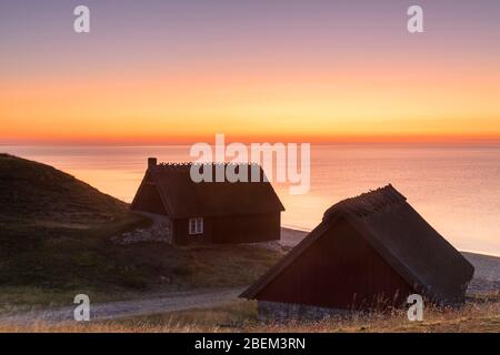 Deux cabanes de pêche au lever du soleil en été le long de la côte de la mer Baltique à Havaeng / Haväng, Österlen / Oesterlen, Skane / Scania, Suède Banque D'Images