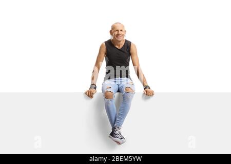 Homme taille basse assis sur un panneau et souriant isolé sur fond blanc Banque D'Images