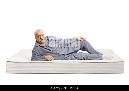 Homme mûr en pyjama allongé sur un matelas de lit et souriant isolé sur fond blanc Banque D'Images