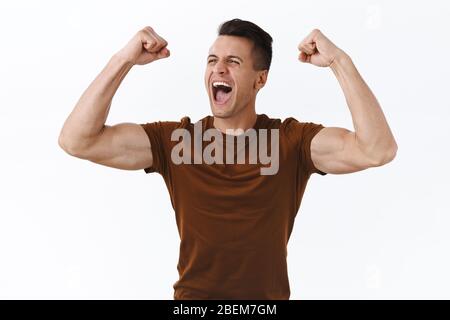 Concept de célébration, sport et fans. Portrait de sympathique homme fort et joyeux qui se hante pour son équipe de football, se levant les mains, chantant et criant Banque D'Images