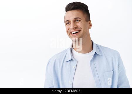 Le concept du bonheur, de la famille et des émotions. Gros plan portrait de beau jeune homme heureux avec coupe élégante, regarder à gauche vide espace avec plaisir Banque D'Images