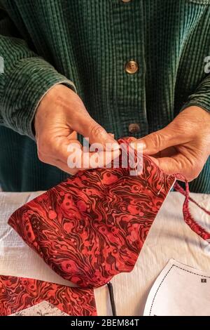 Karen Rentz épinglant un masque en tissu fait maison en préparation à la couture pour préparer à sortir en public pendant la pandémie de Covid-19 dans le micro durement frappé Banque D'Images