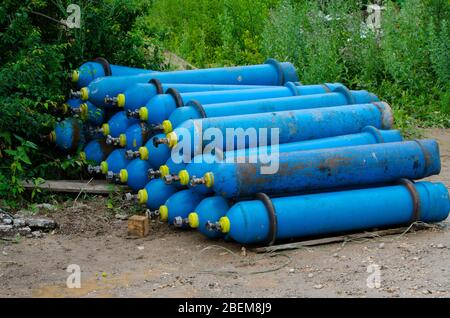 Bouteilles d'oxygène industrielles bleues sur le sol dans la boue stockage dangereux des déchets industriels mise au point sélective Banque D'Images