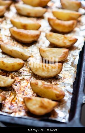 Tranches de pommes de terre cuites sur du papier d'aluminium dans le four jusqu'à ce qu'elles soient dorées. Banque D'Images