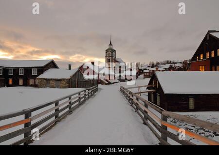 Vue sur la ville minière historique de Røros avec l'église Bergstadens Ziir et les maisons en bois traditionnelles en hiver, Norvège. Banque D'Images