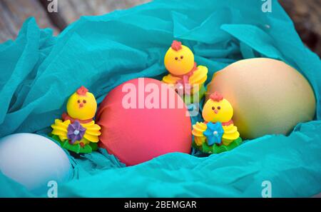 Trois œufs de pâques doux et trois œufs de Pâques colorés sur un chiffon bleu dans un panier Banque D'Images