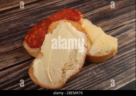 Pain grillé au blé frais avec beurre, fromage et saucisse sur fond de bois. Gros plan Banque D'Images