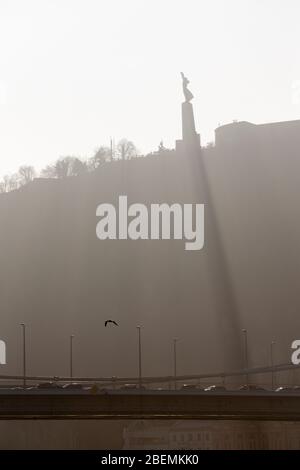 La Statue de la liberté (Statue de la liberté) sur la colline Gellért jette une ombre juste après le lever du soleil avec Liberty Bridge au premier plan, Budapest Banque D'Images