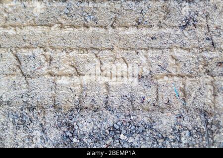 Dans une zone de stationnement rural remplie de petits graviers, les traces de pneus sont vues impressionnés dans la boue par une journée humide. Banque D'Images