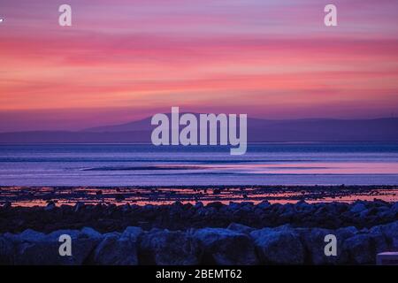 Heysham, Lancashire, Royaume-Uni. 14 avril 2020. Spectaculaire après la lueur derrière les South Lakeland Fells, en face de la baie de Morecambe apporte à un mardi proche. Crédit: Photographier Nord/Alay Live News Banque D'Images