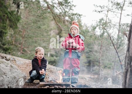 Frère et sœur cuisant des guimauves sur un feu de camp en Suède Banque D'Images