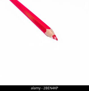 Un crayon de bois rouge unique placé sur un fond de papier blanc isolé Banque D'Images