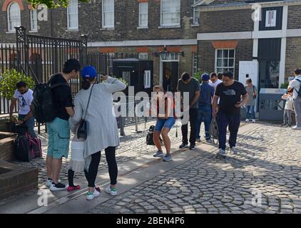 Un visiteur prend une photo d'une famille se trouvant sur la ligne Greenwich Meridian à l'Observatoire royal de Greenwich à Londres, au Royaume-Uni Banque D'Images