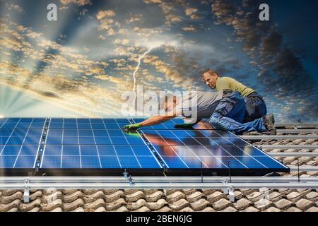 Portrait des travailleurs qui installent des panneaux photovoltaïques sur le toit Banque D'Images