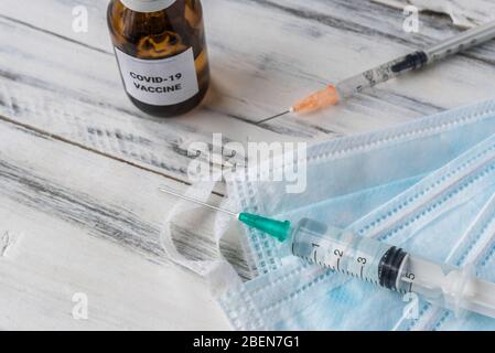 Vaccin contre le covid-19 du coronavirus avec seringues sur le fond des masques faciaux. Banque D'Images