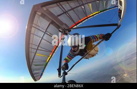 Le pilote de planeur suspendu sur l'aile colorée fait de photo selfie haut au-dessus du sol. Concept d'isolement personnel et d'activité de distanciation sociale. Sport extrême Banque D'Images