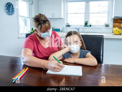 Éclosion de coronavirus. Verrouillage et fermeture des écoles. Mère aidant la fille ennuyée avec masque de visage étudiant des cours en ligne à la maison. COVID-19 pandémie FO Banque D'Images