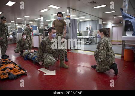 NEW YORK (13 avril 2020) Ensign Hannah Dubois, membre de la zone de réception des victimes à bord du navire hospitalier du Commandement du transport maritime militaire USNS Comfort (T-AH 20), dirige un groupe de marins qui pratiquent des procédures de transport appropriées des patients. Le confort s'occupe des patients souffrant de traumatismes, d'urgence et de soins urgents sans égard à leur statut COVID-19. Comfort travaille avec la Station médicale de New York de Javits comme système intégré pour soulager le système médical de New York City, à l'appui du soutien de défense des autorités civiles du Commandement Nord des États-Unis en réponse à la pandémie de COVID-19. Banque D'Images