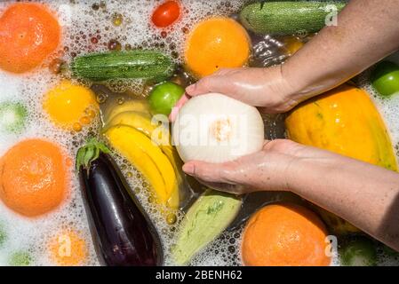 Lavage des fruits et légumes dans de l'eau savonneuse pour la désinfection du coronavirus. Banque D'Images