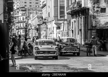 Une paire de voitures classiques vertes au Centro Havana (Cuba) émerge des ombres coulées par le soleil levant comme elles l'avaient fait vers la vieille ville de Novembe Banque D'Images