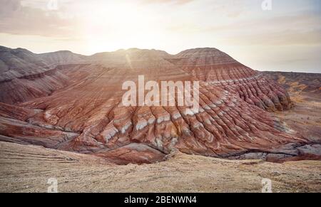 Vue aérienne de montagnes à rayures rouges de forme pyramidale au lever du soleil dans le parc du désert Altyn Emel au Kazakhstan Banque D'Images