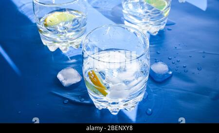 Verres d'eau rafraîchissante avec glace et citron sur fond bleu. Concept de chaleur, frais. Lumière naturelle, espace de copie Banque D'Images