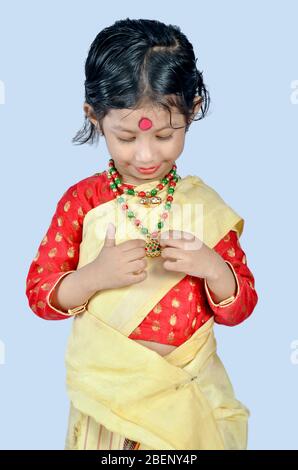 Une petite fille en costume traditionnel d'Assamois montrant des bijoux traditionnels d'Assamois pendant la célébration du festival de Rongali Bihu à Assam Banque D'Images