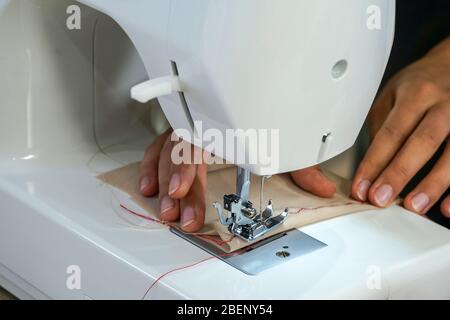 La couturière de créateur de mode est décorée avec soin d'un motif rouge en soie sur un tissu beige fin. Banque D'Images