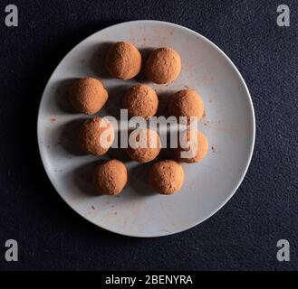 Boules de cacao au chocolat sur une plaque bleue, saupoudrées de poudre de cacao. Pose plate Banque D'Images