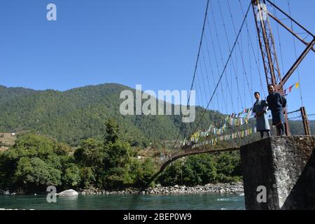 Le personnel d'Aman Resorts se tient sur un pont suspendu au-dessus de la rivière Mo Chhu au nord de Punakha, au Bhoutan Banque D'Images