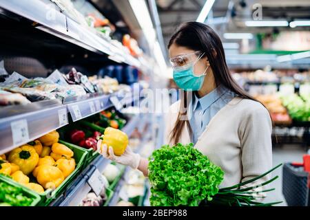 Femme avec masque hygiénique acheter dans supermarché épicerie pour les verts frais, shopping pendant la pandémie.Source naturelle de vitamines et minéraux.Pla Banque D'Images