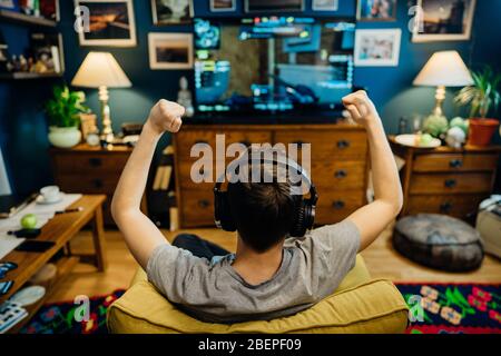 Jeune joueur esport professionnel avec casque jouant et gagnant de la compétition Internet MMORPG cyber championnat dans la stratégie de tir de première personne sur Banque D'Images