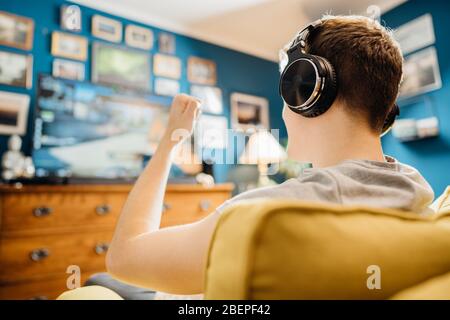 Jeune joueur esport professionnel avec casque jouant et gagnant de la compétition Internet MMORPG cyber championnat dans la stratégie de tir de première personne sur Banque D'Images