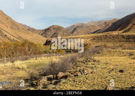 Une gorge dans les montagnes avec une rivière. Rivière Kokemeren dans le district de Jumgal, province de Naryn, au Kirghizstan. Pierres et buissons sur la rive de la rivière. Banque D'Images