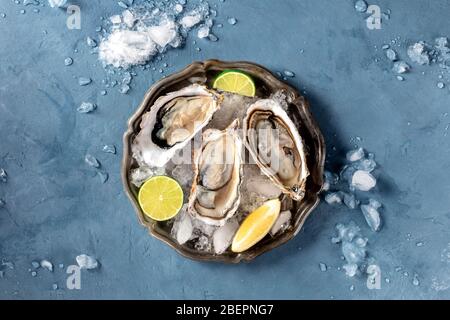 Huîtres sur glace, tiré du dessus sur une ardoise, avec citron et citron vert Banque D'Images