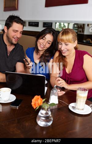 Le groupe avec netbook et les téléphones portables est en train de s'amuser dans le café Banque D'Images