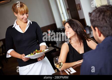 La serveuse apporte une salade à une femme au restaurant Banque D'Images