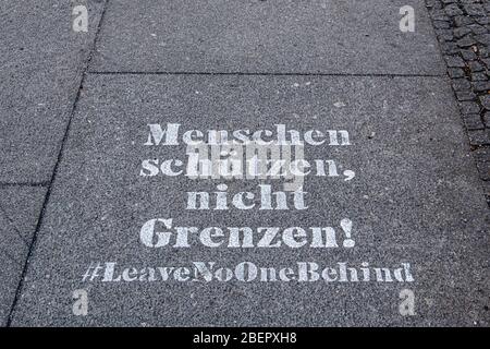 Berlin, Mitte, COVID-19 message pandémique.scenilé sur la chaussée. Menschen Schutzen nicht grenzen. #laissez personne derrière Banque D'Images