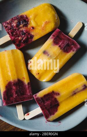 Les popsicles faits maison de fruits sont à base de mangue fraîche, de cassis et de lait de coco. Dessert d'été végétalien sain. Banque D'Images