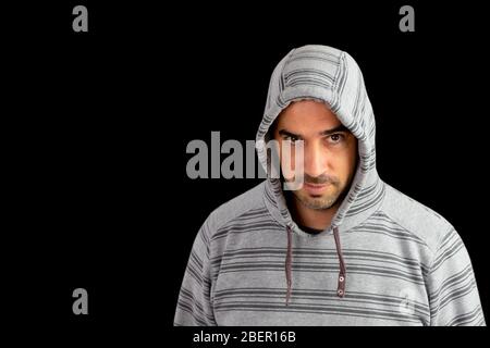 Homme barbu dans un sweat à capuche posé avec un fond noir Banque D'Images