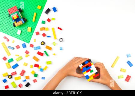 Vilnius, Lituanie - 17 août 2019: Les mains d'enfants jouant avec des briques Lego colorées blocs sur la table blanche Banque D'Images