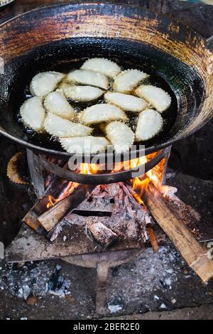 Pâte boulettes friture dans l'huile sur poêle à bois. Des stands de nourriture asiatiques sur le marché d'Indein, au Myanmar. Orientation verticale Banque D'Images