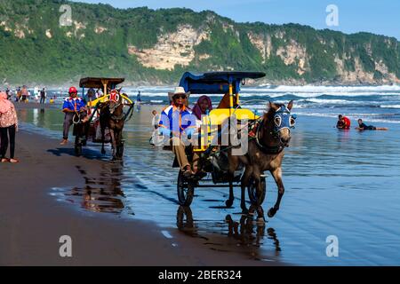 Les Indonésiens qui apprécient les promenades en chevaux et en calèche sur la plage de Parangtritis, Yogyakarta, Indonésie. Banque D'Images