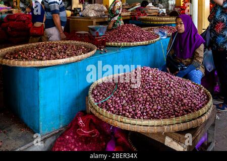 Une femme vend des oignons frais d'UN marché de Stall à l'intérieur du marché de Beringharjo, Yogyakarta, Java, Indonésie. Banque D'Images