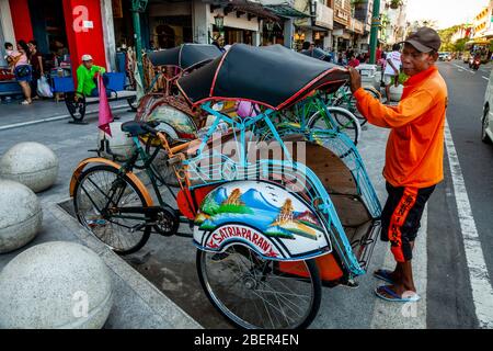 Un becak traditionnel (cycle Rickshaw) et chauffeur, rue Malioboro, Yogyakarta, Indonésie. Banque D'Images