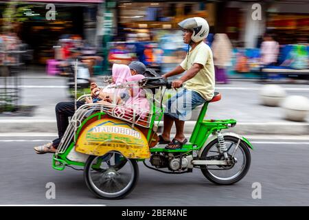 Taxi et passagers de moto, rue Malioboro, Yogyakarta, Indonésie. Banque D'Images