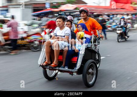 Taxi et passagers de moto, rue Malioboro, Yogyakarta, Indonésie. Banque D'Images