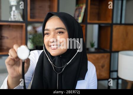 magnifique médecin musulman travaillant dans sa clinique à l'aide d'un stéthoscope Banque D'Images