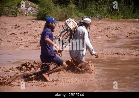 Peshawar, Pakistan. 15 avril 2020. Pakistanais marche dans les eaux d'inondation après de fortes précipitations. Les résidents de la région aident les gens à traverser les vannes. (Photo de Hussain Ali/Pacific Press) crédit: Agence de presse du Pacifique/Alay Live News Banque D'Images