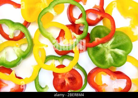 Plein cadre légumes abstraits fond - vue de dessus des poivrons tranchés multicolores sur un fond blanc Banque D'Images